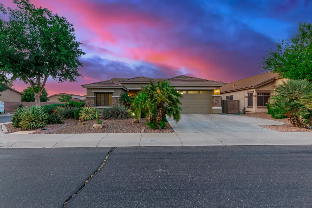 An exterior shot showcasing the house facade with palm trees and well-maintained landscaping. The spacious porch, surrounded by natural beauty, is ideal for watching sunsets and hosting gatherings, capturing the welcoming spirit of the neighborhood.