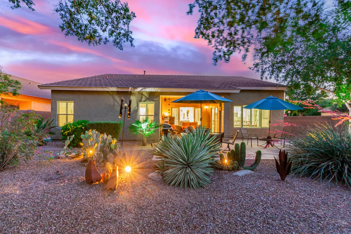 A tranquil patio framed by green plants, stylish umbrellas, ample outdoor seating, and decorative lights. The scene is inviting for both relaxing mornings and lively evening gatherings, with a sense of privacy and comfort ideal for couples or small groups.