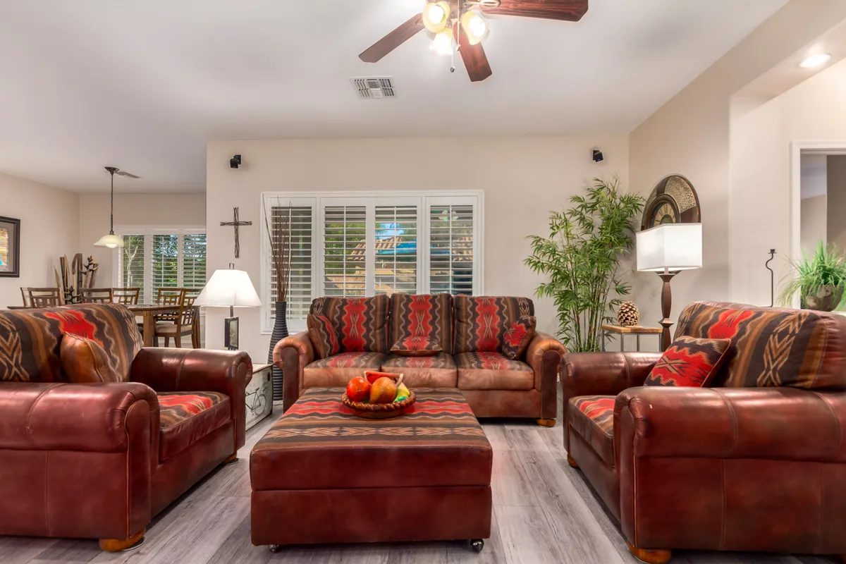 A cozy living space with leather sofas, a coffee table topped with fruit, a decorative lamp, and a potted plant. The room exudes warmth and comfort, with thoughtful touches that invite relaxation or socializing. Ample light and subtle décor create an elegant yet welcoming ambiance.